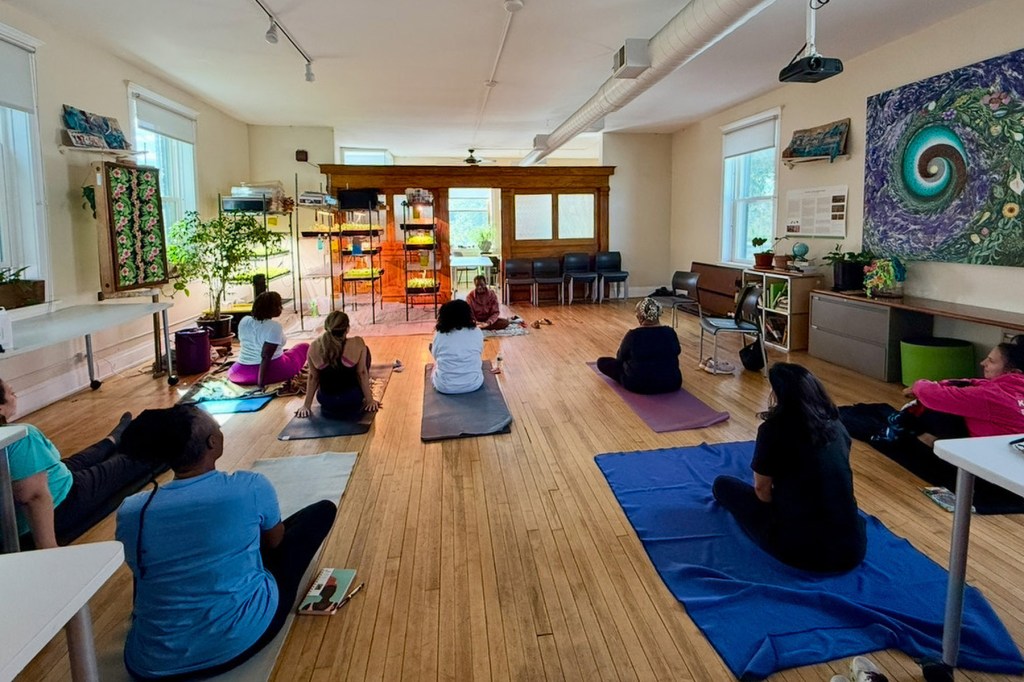 A group of people sit on the floor doing yoga.